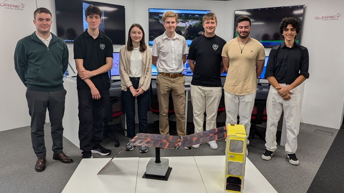 Some of the Surrey students involved with making the Jovian-1 satellite stand in the Surrey Space Centre's Ground Station with a life-sized model of the satellite in front of them