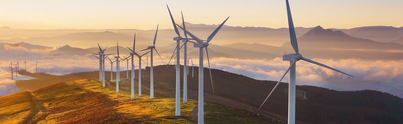 Wind turbines on top of a hill at sunset