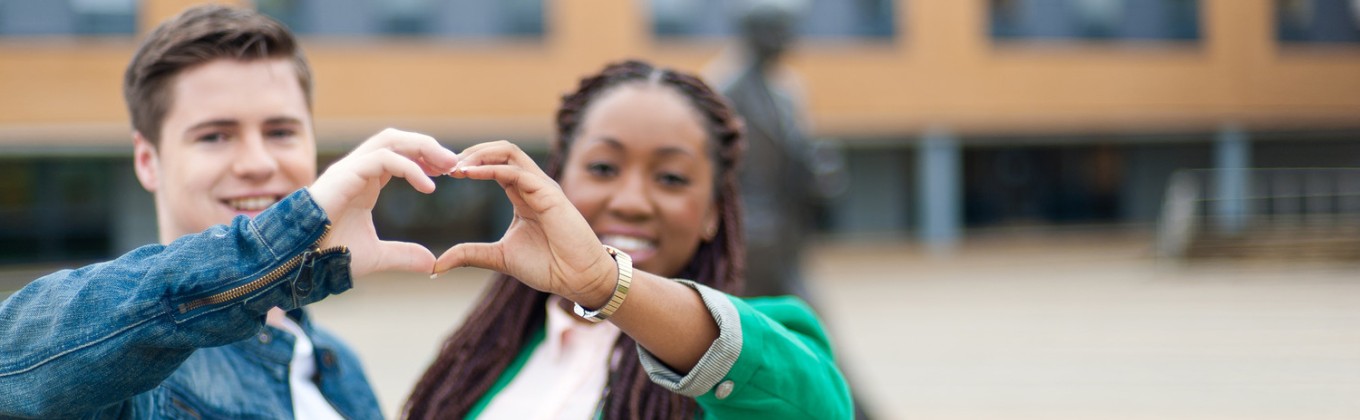Two students are making a heart with their hands
